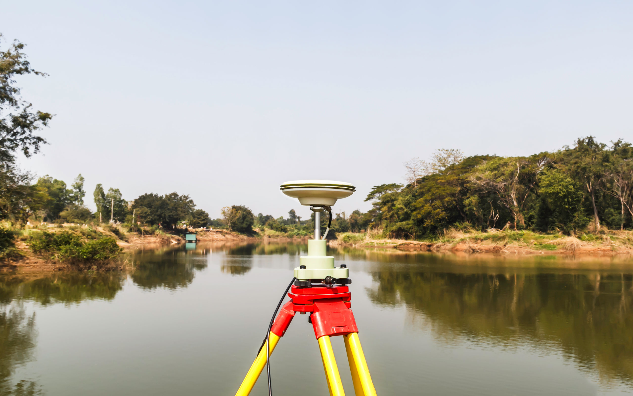 Surveyor's GNSS receiver mounted on a tripod beside a still lake on the Avalon Peninsula
